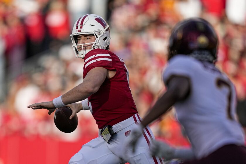 Wisconsin quarterback Graham Mertz (5) passes as Minnesota defensive back Beanie Bishop (7) pressures during the first half of an NCAA college football game Saturday, Nov. 26, 2022, in Madison, Wis. (AP Photo/Andy Manis)
