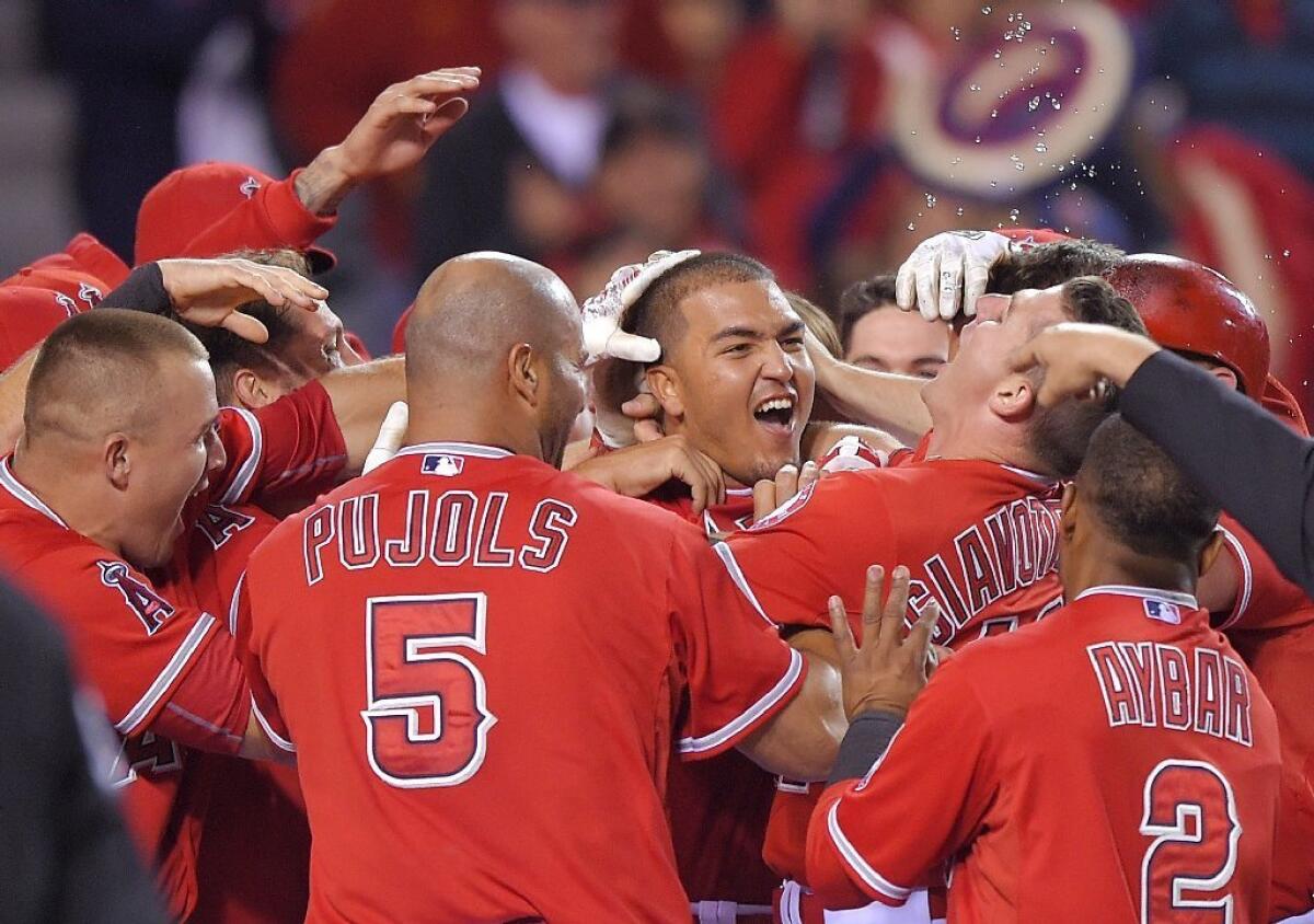 Angels rookie catcher Carlos Perez is surrounded by teammates after hitting a walk-off home run to win the game during the ninth inning against the Mariners on May 5.