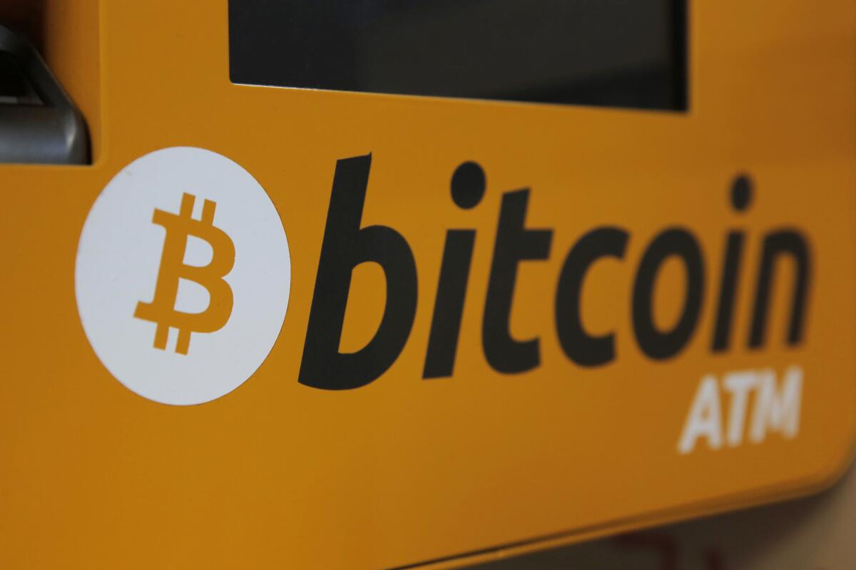 A bitcoin logo is shown is displayed on an ATM.