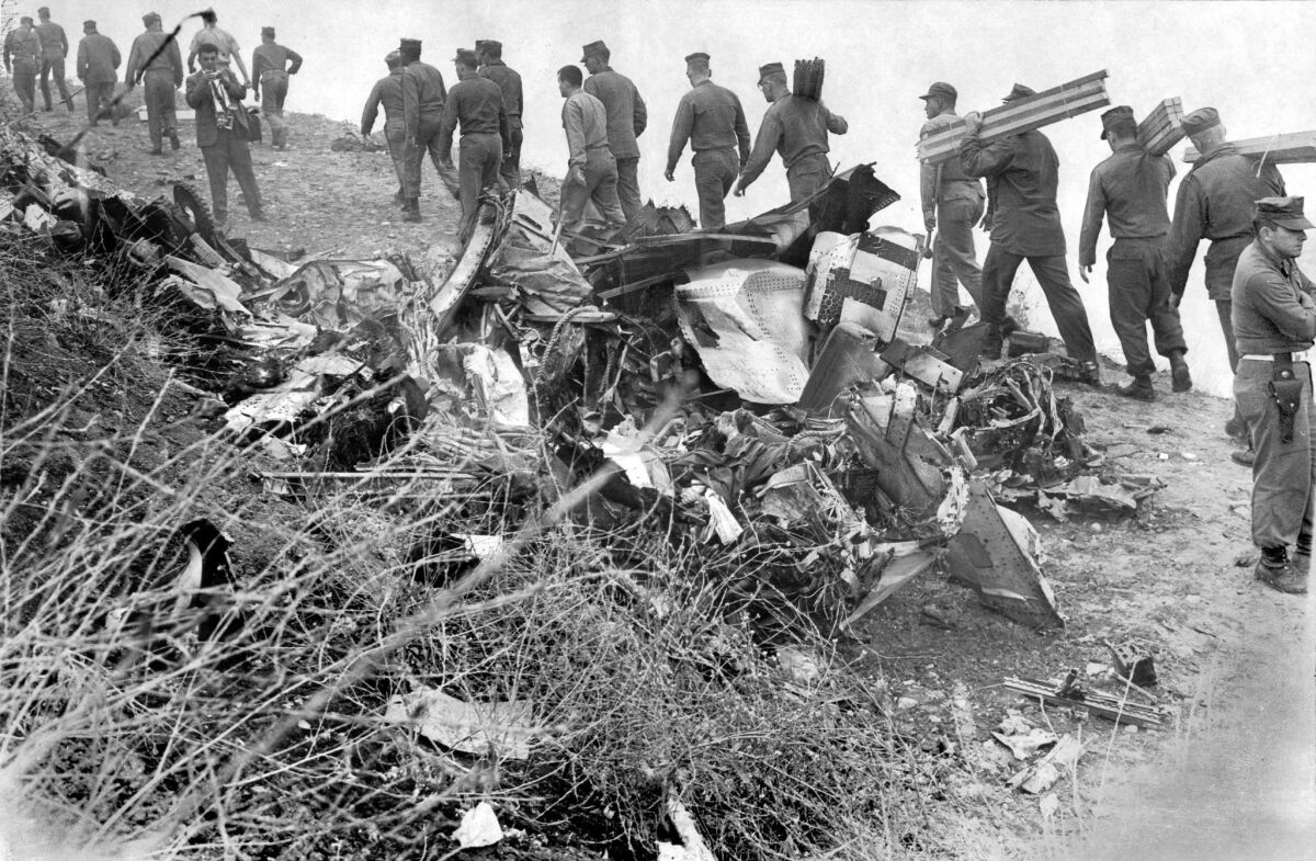 In this photo from the June 26, 1965, edition of The Times, Marines walk past the wreckage of an Air Force C-135 Stratolifter that had slammed into a hillside after taking off from El Toro Marine Corps Air Station. All 84 men aboard were killed in what remains Orange County's deadliest air disaster.