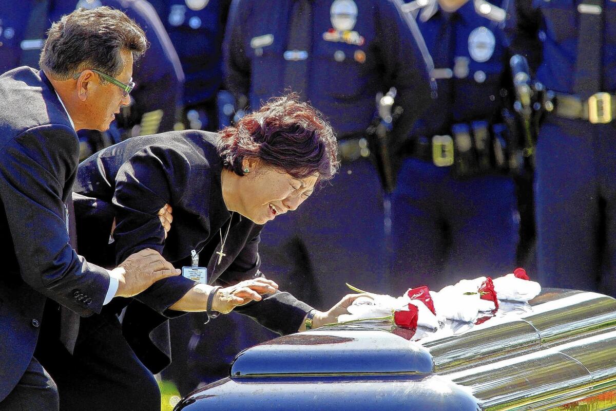 LAPD Officer Nicholas Lee's parents, Heung, left, and Choung, visit his casket during a graveside service at Forest Lawn Memorial Park in Glendale. Lee was killed in a traffic accident last week.