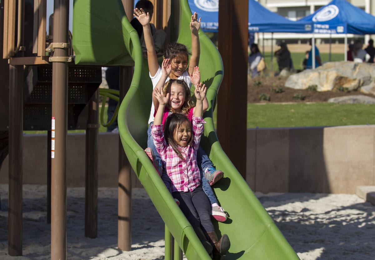 Kayla Tougas, 8, left, Lucy Levin, 6, and Tessa Tougas, 6, have fun on the new playground equipment during the grand opening and dedication ceremony of Sunset Ridge Park on Saturday.