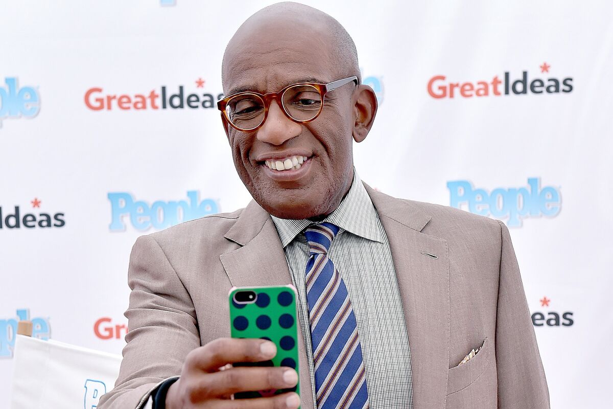 "Today" show host Al Roker holds up a cellphone at an event.
