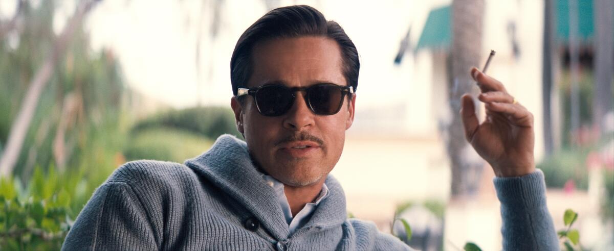 Brad Pitt wears sunglasses and holds a cigarette in a scene from "Babylon."