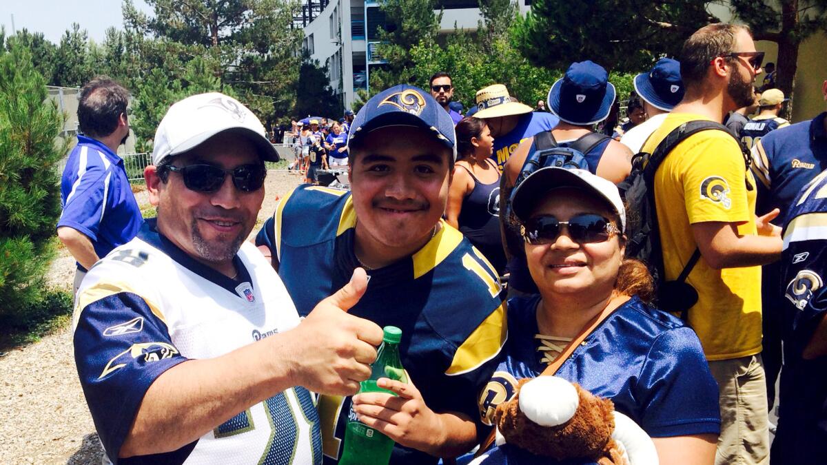 Frank Mendoza gives the thumbs-up as he joins son Anthony and wife Ada near the front of the line to enter the Rams' first training session at UC Irvine on Saturday.