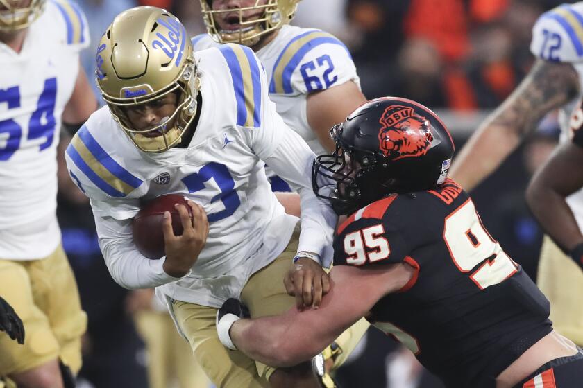 UCLA quarterback Dante Moore (3) is brought down by Oregon State defensive lineman.