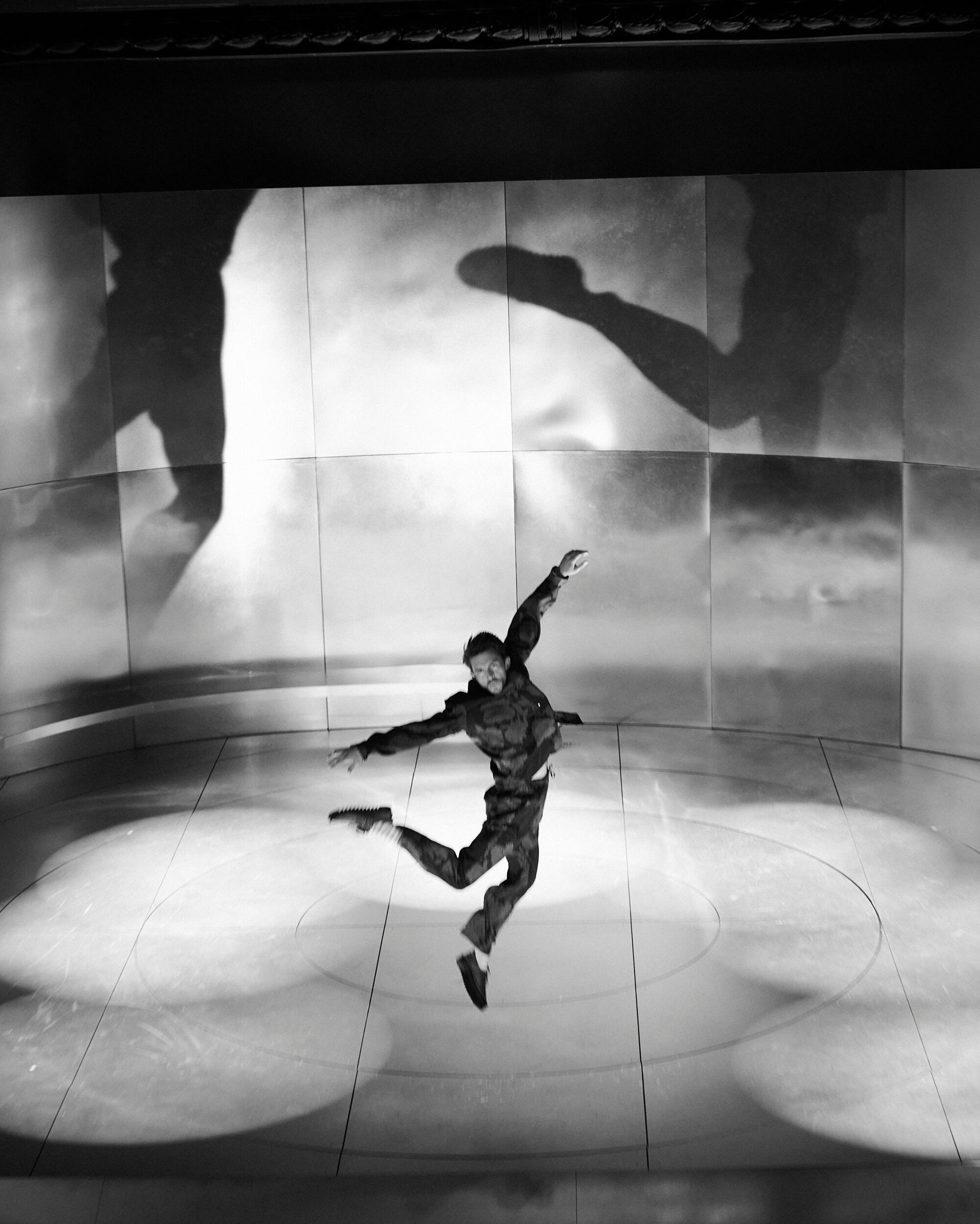 A man jumps in the air on a theater stage.