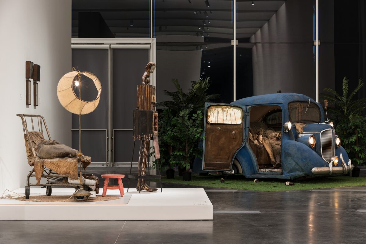 Installation of works showing a chair and old blue car by Ed Kienholz on display