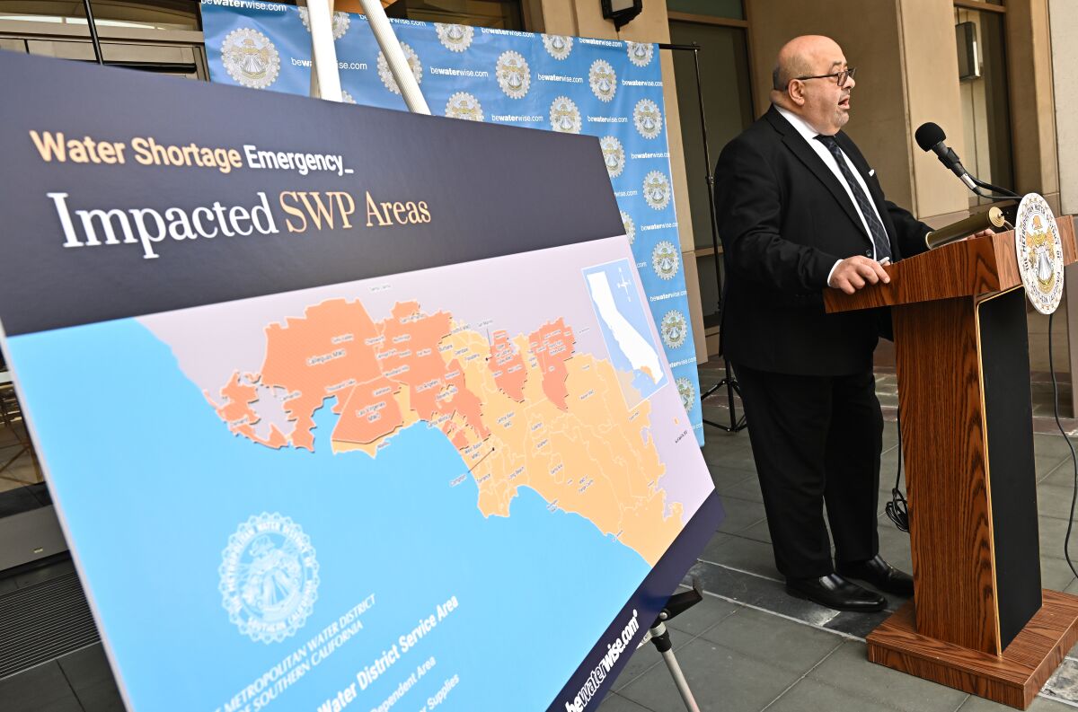 A man stands at a lectern next to a map of Southern California