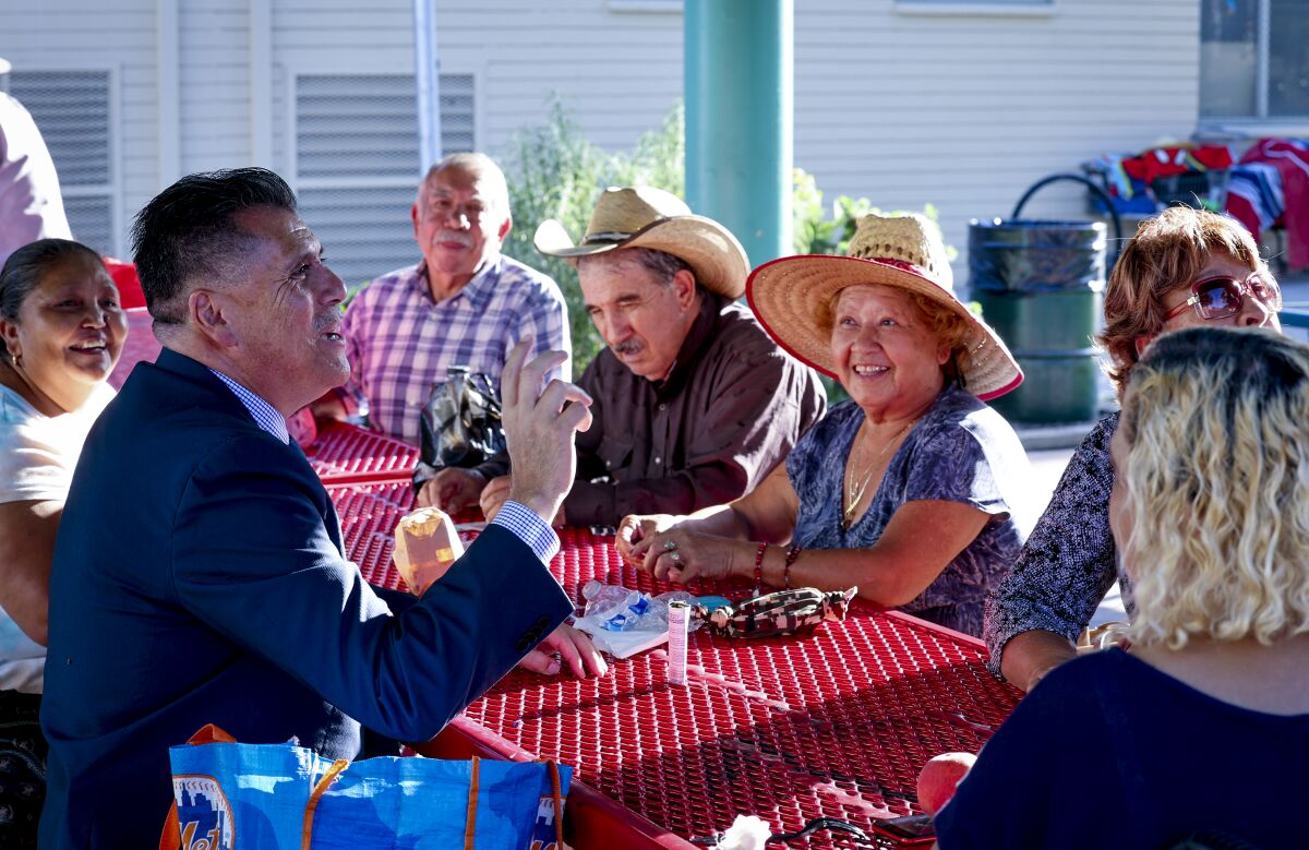 L.A. County sheriff candidate Robert Luna, left, talks with local residents at Ruben Salazar Park in East L.A.