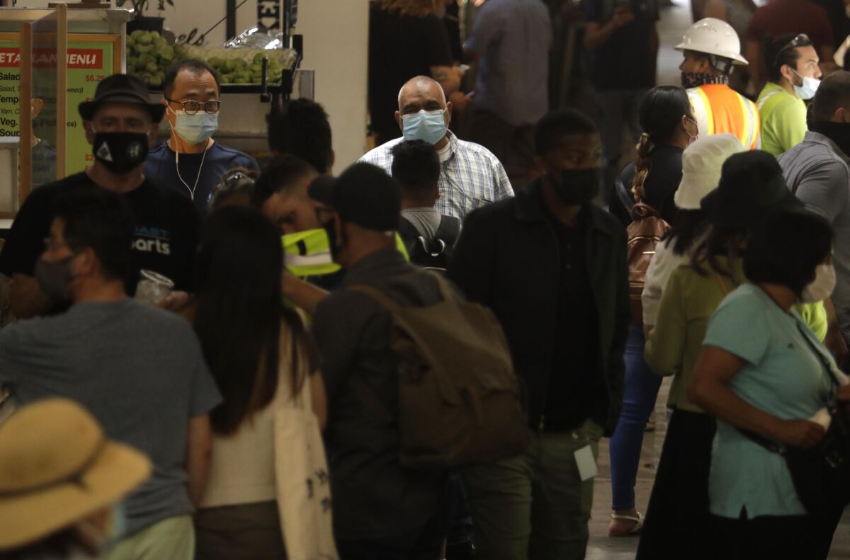 A mix of masked and unmasked people explore Grand Central Market in downtown Los Angeles on June 15. 