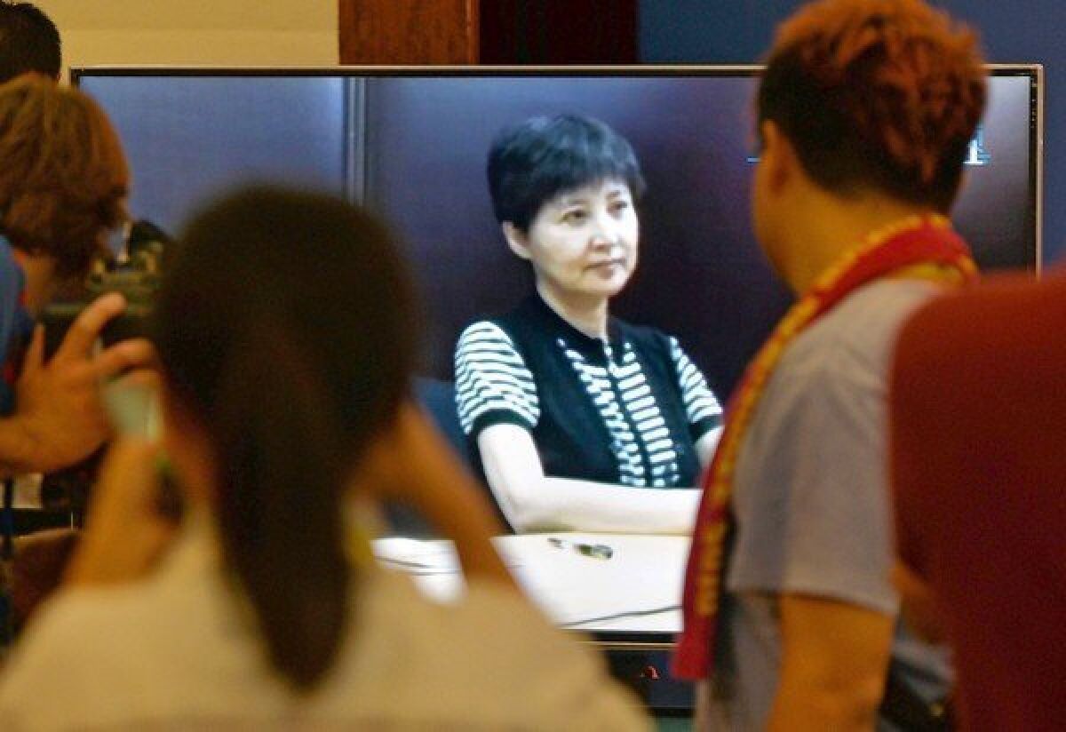 Journalists watch Gu Kailai, center, as her recorded testimony is presented during the corruption trial of her husband, Bo Xilai, in court in Jinan, China.
