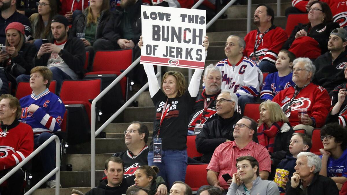 A Carolina Hurricanes fan holds a sign saying she loves this "Bunch of Jerks."