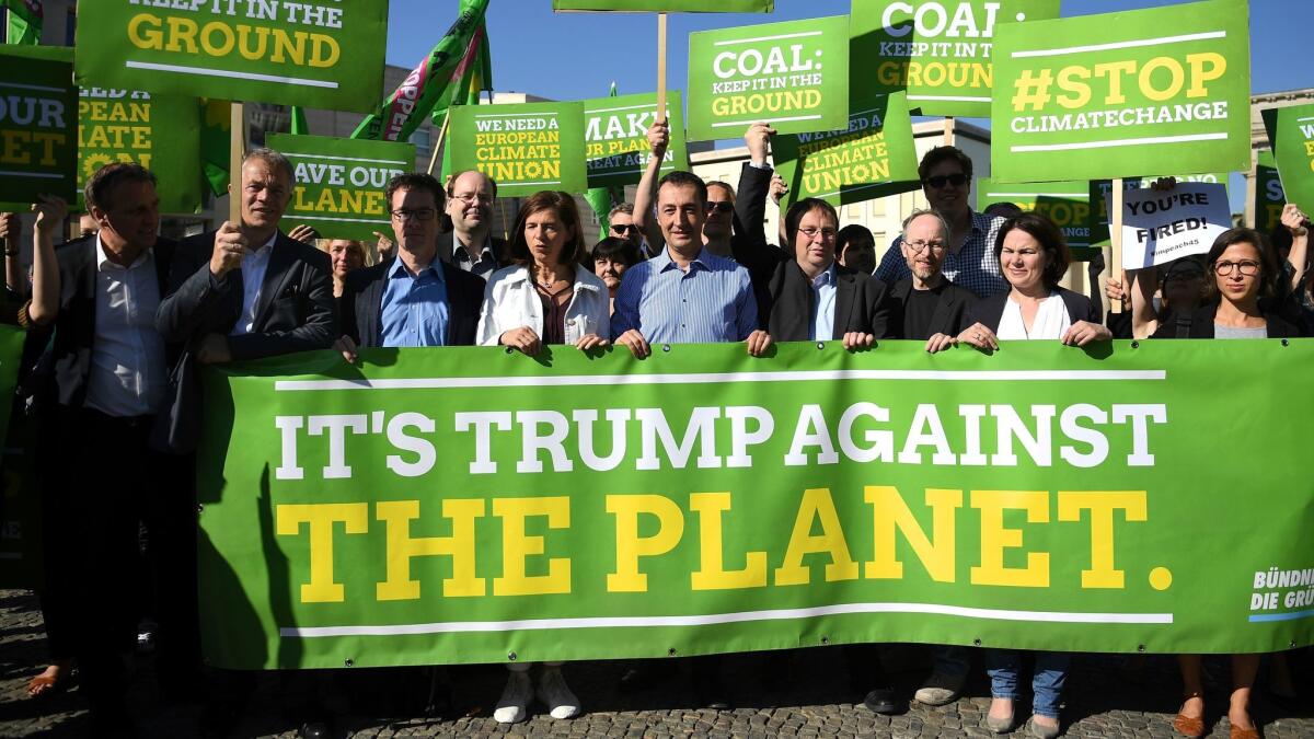 Parliamentary candidates from Germany's Green Party, Katrin Goering-Eckardt, center left, and Cem Ozdemir, center, protest President Trump's decision to exit the Paris climate agreement in front of the U.S. embassy in Berlin on June 2, 2017.