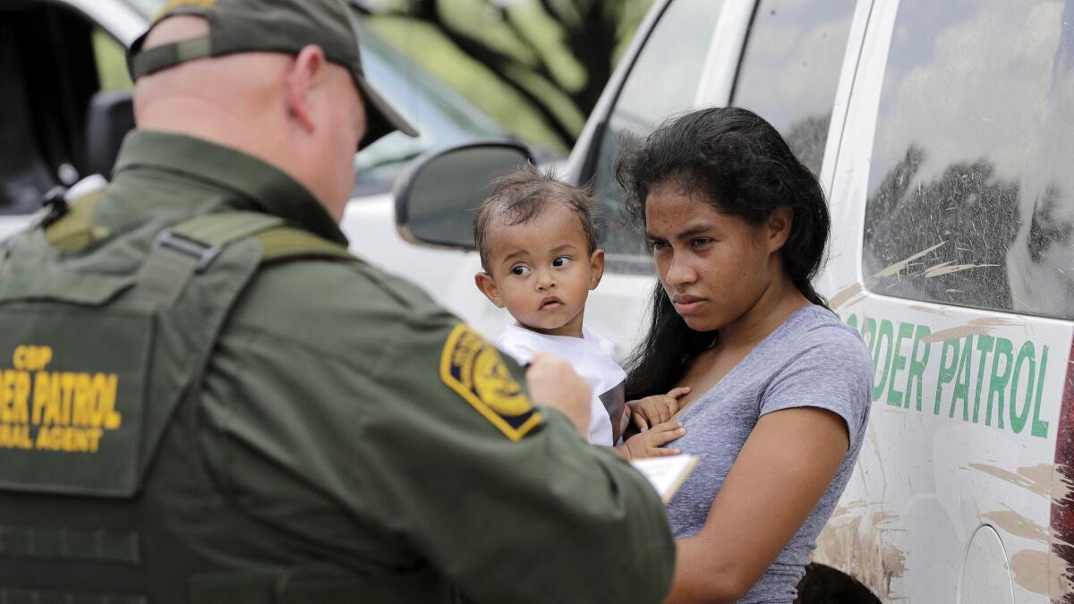 A mother from Honduras who illegally crossed the border near McAllen, Texas, with her 1-year-old child surrenders to U.S. Border Patrol agents in June.