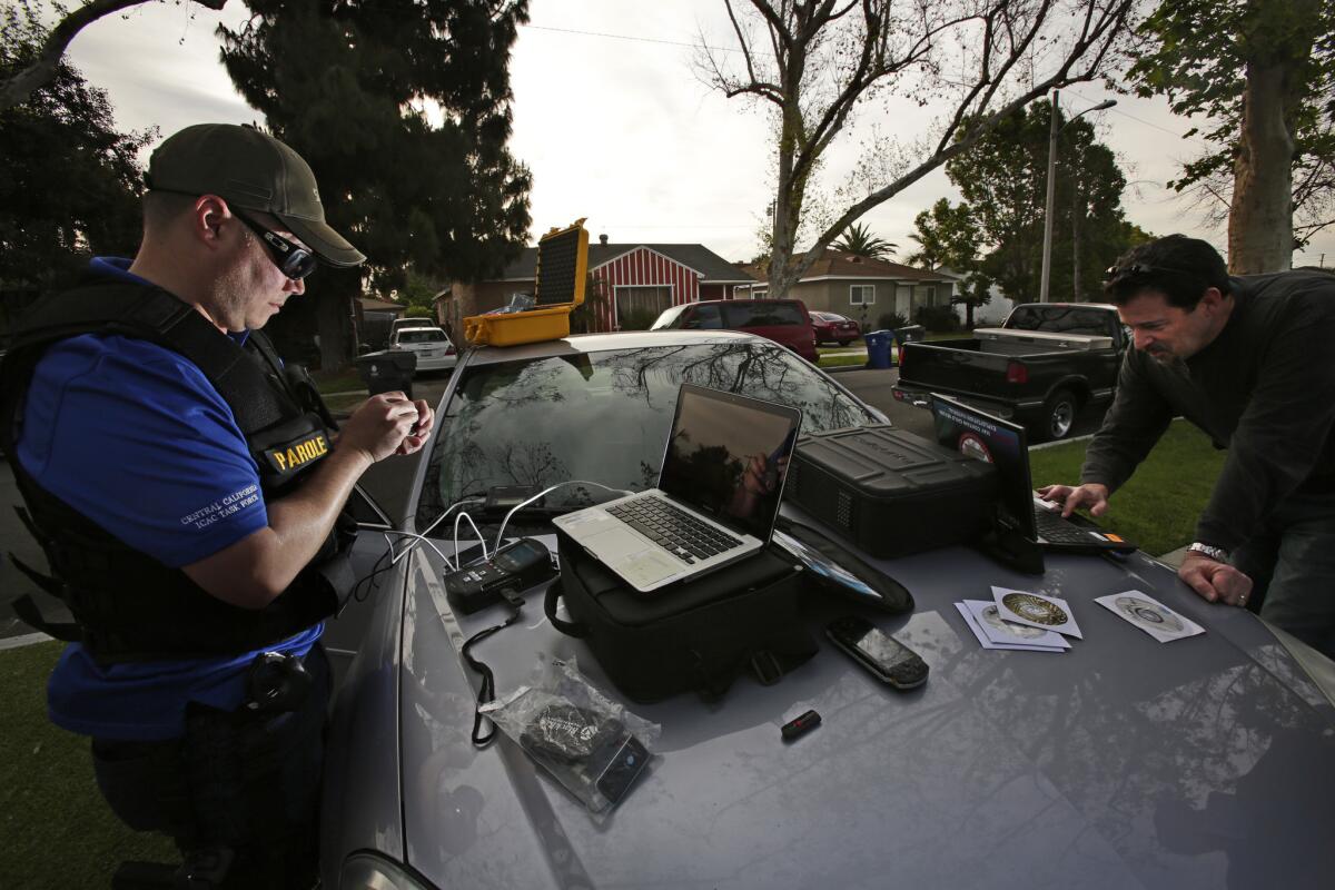 Parole agents use a Cellebrite and a laptop to check a sex offender's mobile phone, thumb drives and laptop for pornographic material during a sweep in April 2014. (Irfan Khan / Los Angeles Times)