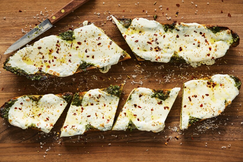 Slices of French bread pizza with pesto and mozzarella lie on a plate.