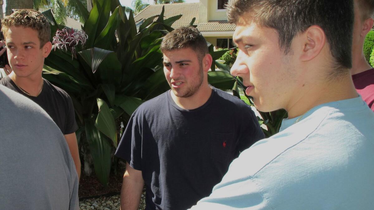 Jonathan Blank, centro, de 16, habla con amigos fuera de su hogar en Parkland.