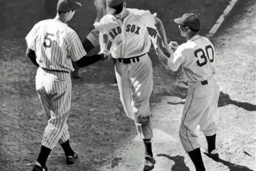 FILE - In this file photo made July 8, 1941, Ted Williams, center, is greeted at home plate by teammate Joe DiMaggio (5) and coach Marv Shea after hitting a dramatic ninth-inning home run to give the American League a 7-5 victory over the National League in the All-Star Game at Briggs Stadium in Detroit. (AP Photo, File)