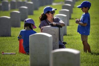 Los Angeles, CA - September 24: A UNCLA alumni Jackie Toenniessen, 36, center, brought her children Isabelle, 8, left, and Nicolas, 4, Los Angeles National Cemetery to on clean veterans' headstones on Saturday, Sept. 24, 2022 in Los Angeles, CA. (Irfan Khan / Los Angeles Times)