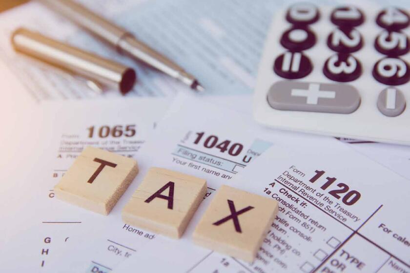 Tax season with wooden alphabet blocks, calculator, pen on 1040 tax form background