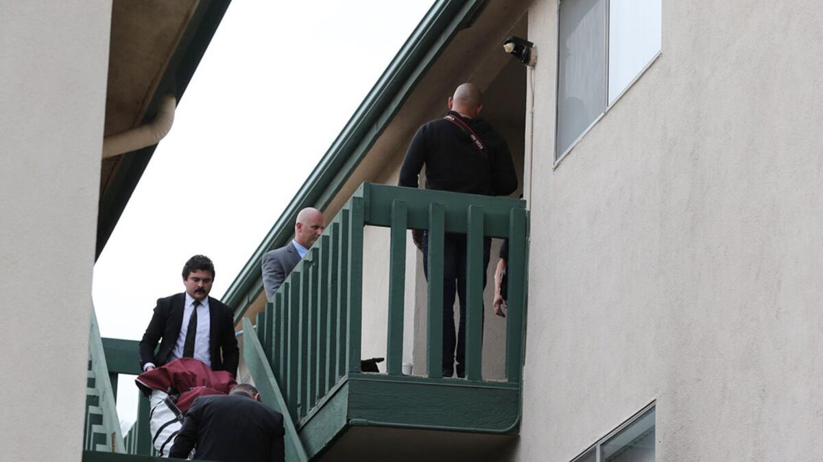 Investigators with the coroner's office remove a body from a Seal Beach apartment Monday morning.