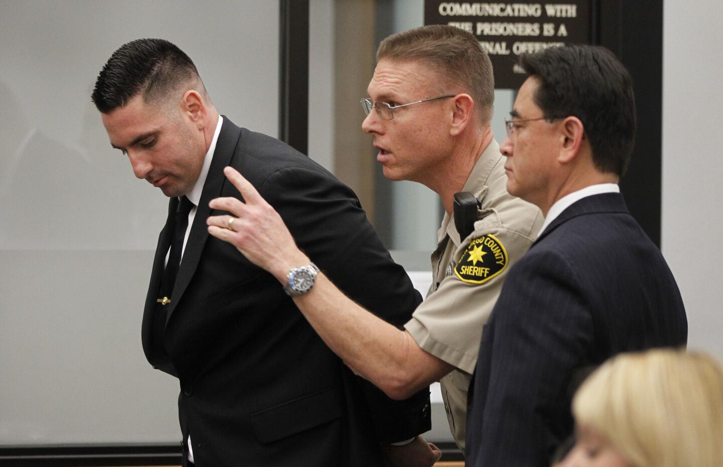 After being handcuffed, former Deputy Richard Fischer, left, is directed out of the courtroom by a court bailiff as he is taken into custody after his arraignment at the Vista courthouse on Thursday.