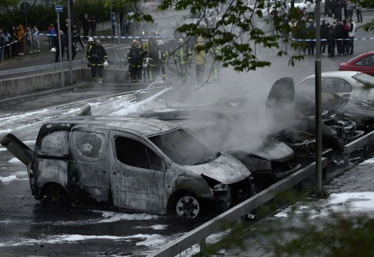 People watch as Swedish firemen extinguish burning cars in the Stockholm suburb of Rinkeby after youths rioted in several suburbs around Stockholm for a fourth consecutive night on Thursday.