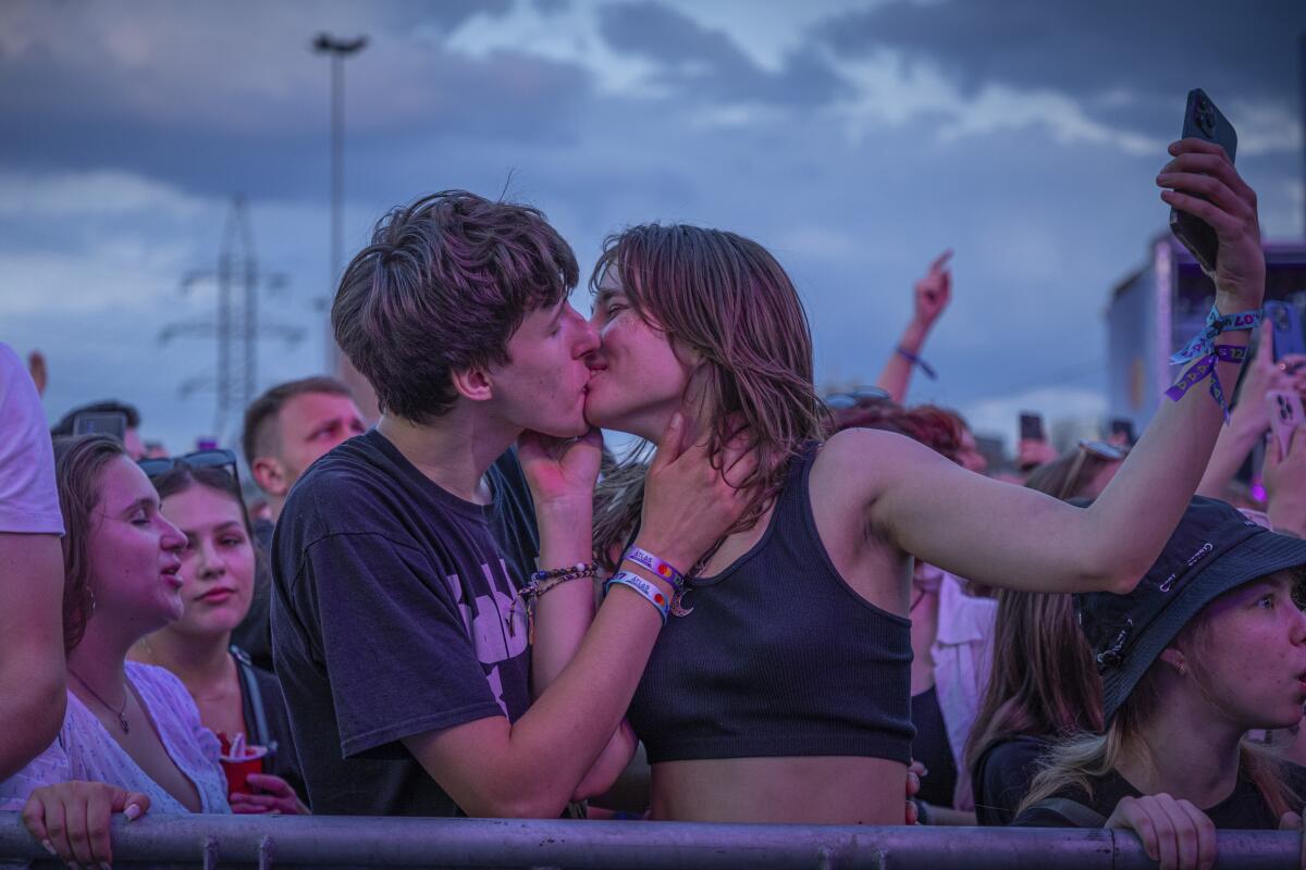 Two young people kiss at a music festival.