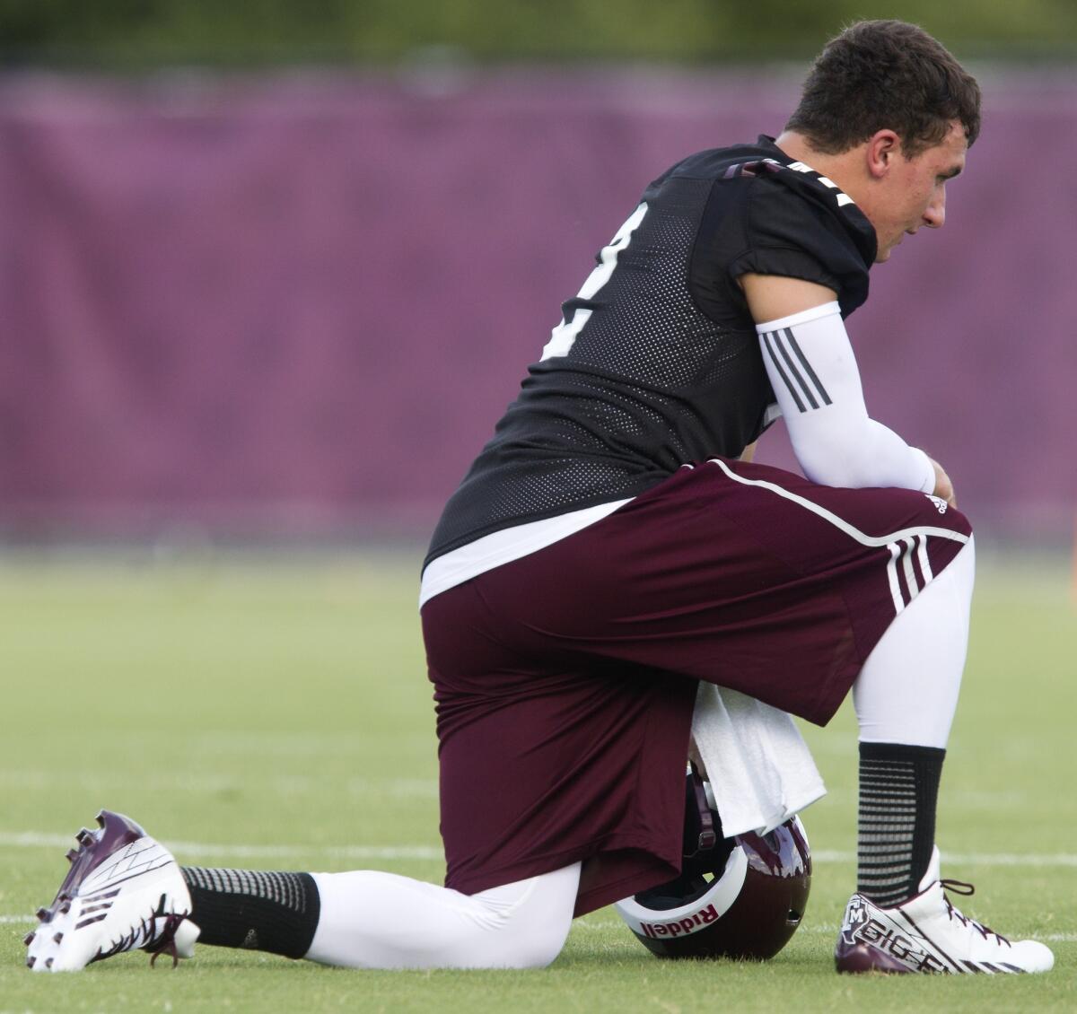 Texas A&M; quarterback Johnny Manziel takes a knee during practice.
