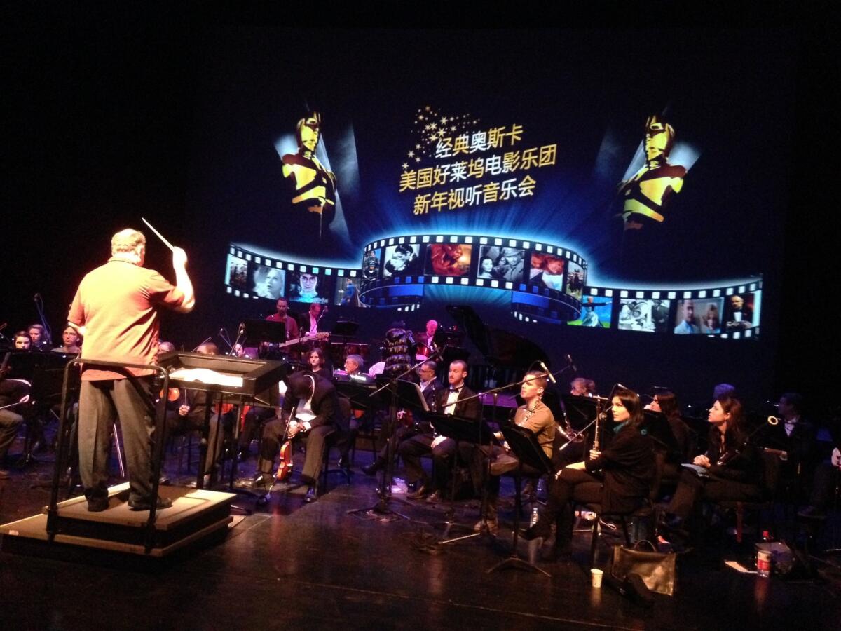 Members of the American Hollywood Film Orchestra rehearse at the National Center for the Performing Arts in Beijing. The screen behind them reads, "Classic Oscar: The American Hollywood Film Orchestra New Year's Audio-Visual Concert."