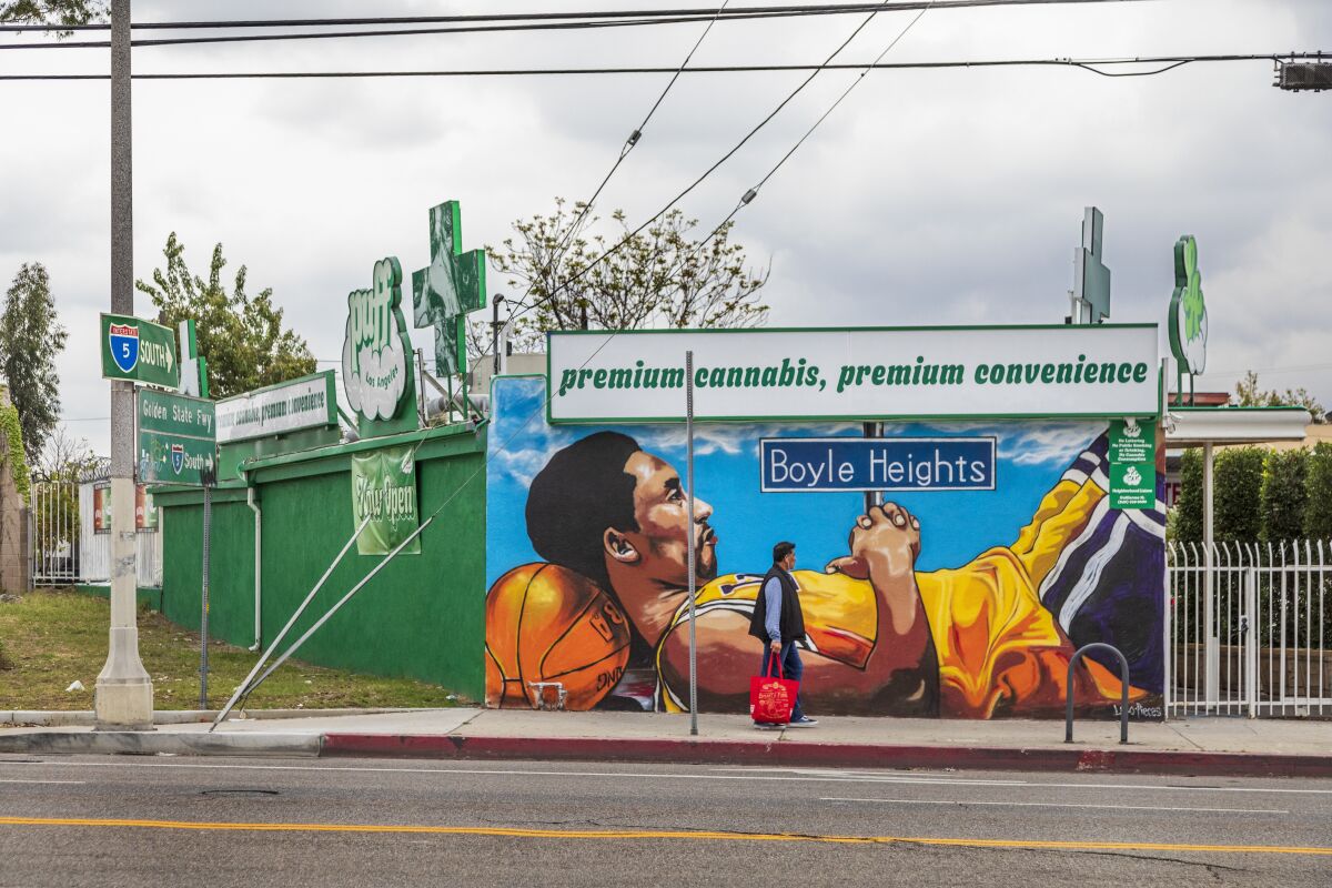 A man walks by Kobe Bryant's mural in front of the Puff L.A. dispensary in Boyle Heights