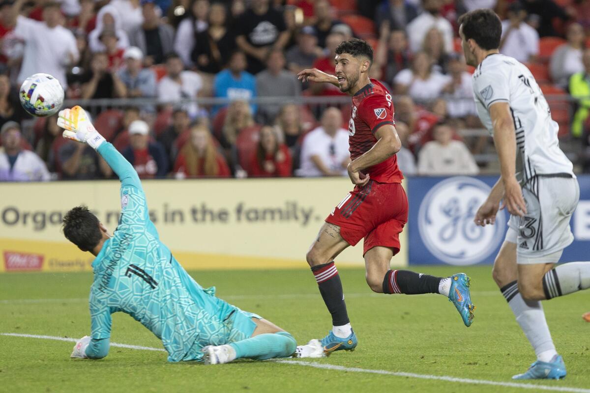 Toronto FC midfielder Jonathan Osorio, center, kicks the ball over San Jose Earthquakes goalkeeper JT Marcinkowski (1) to score his team's second goal during second-half MLS soccer match action in Toronto, Saturday, July 9, 2022. (Chris Young/The Canadian Press via AP)