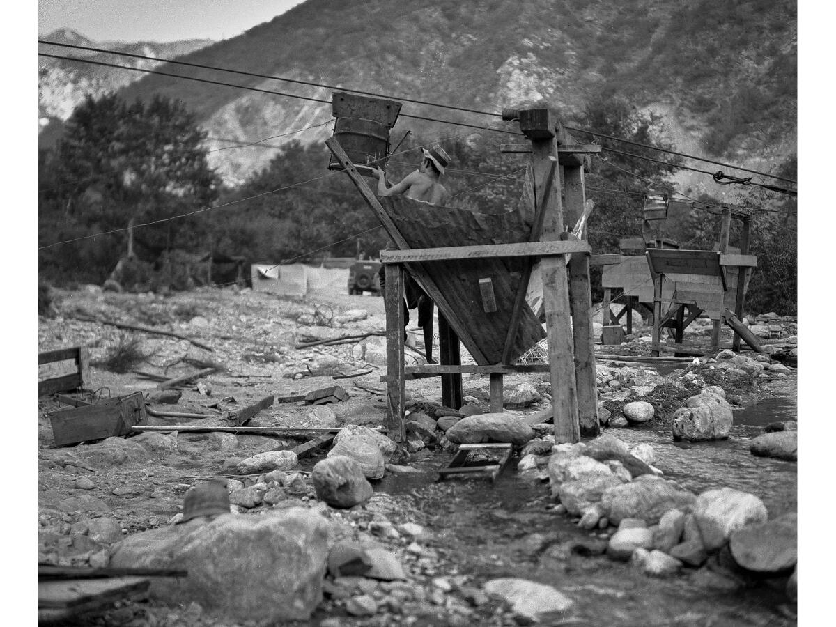 Gold miner Joey Brandt works with a conveyer bucket, a hopper and a sluice box over a stream in San Gabriel Canyon.