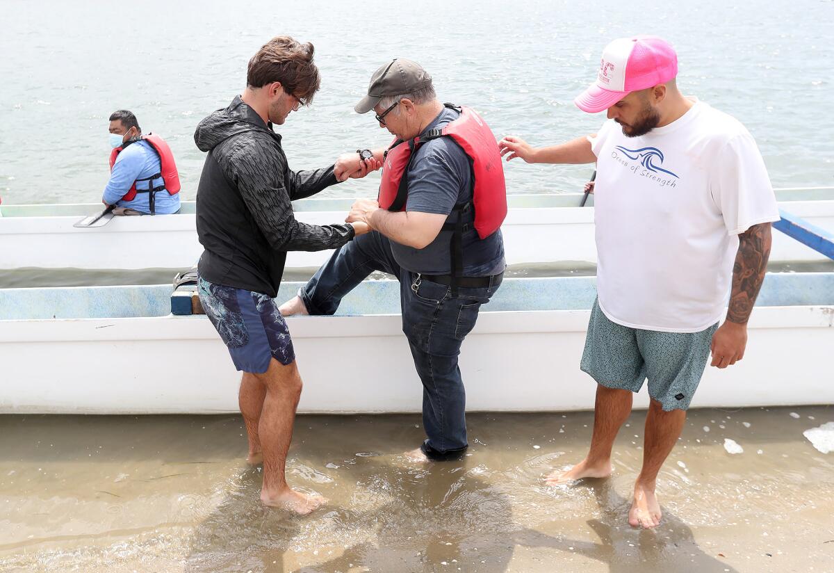 Staff members Andrew Bader, left, and Efrain Becerra, right, help client Jeffrey into a canoe on Thursday.