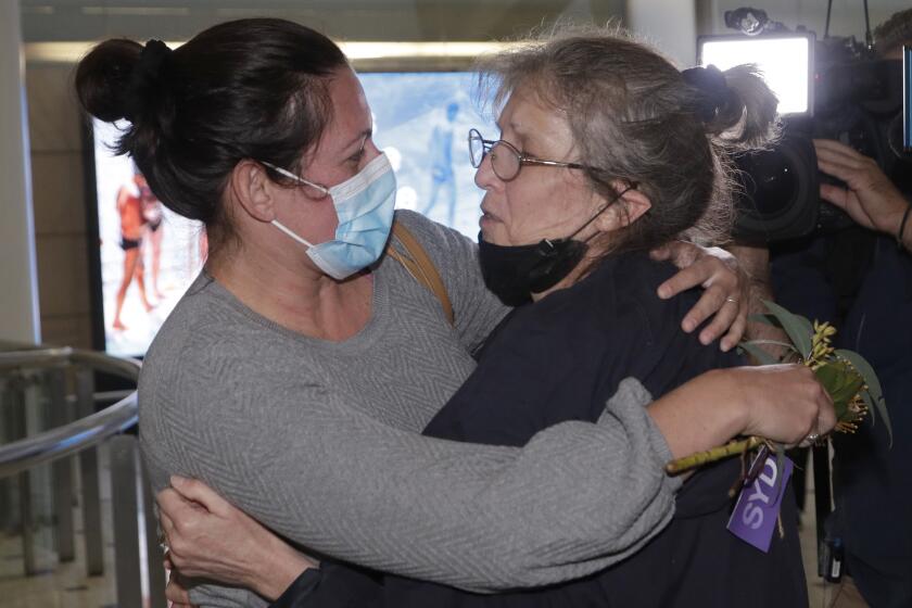 A woman, right, is embraced by. a loved-one after arriving on a flight from Los Angeles at Sydney Airport as Australia open its borders for the first time in 19 months in Sydney, Monday, Nov. 1, 2021. International travel will be initially restricted to Sydney's airport because New South Wales has the highest vaccination rate of any state. (AP Photo/Rick Rycroft)