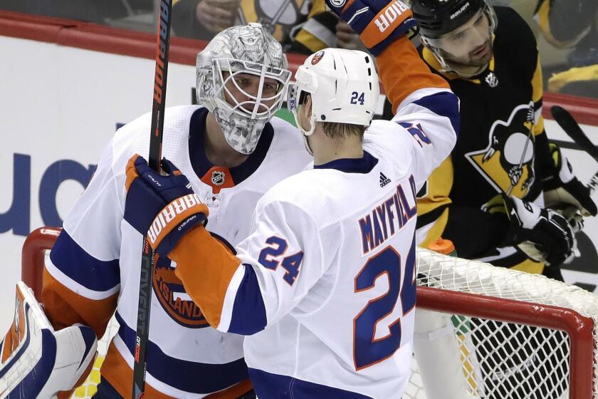 New York Islanders goaltender Robin Lehner, left, celebrates with Scott Mayfield (24) as Pittsburgh Penguins' Zach Aston-Reese skates back to his bench after a 4-1 win over the Pittsburgh Penguins in Game 3 of an NHL first-round hockey playoff series in Pittsburgh, Sunday, April 14, 2019. (AP Photo/Gene J. Puskar)