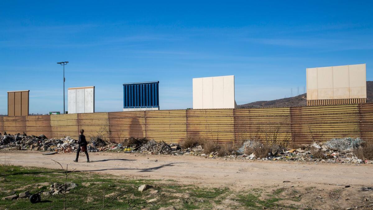 A participant in Christoph Büchel's tour of the border wall prototypes walks along the Mexican side of the border.