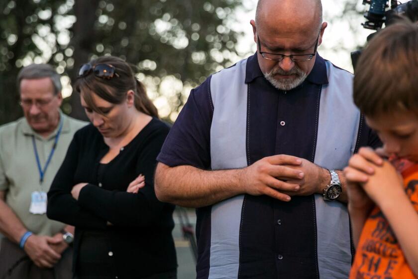 ROSEBURG, ORE. -- SUNDAY, OCTOBER 4, 2015: Local and national church groups, along with community members gather to pray at a makeshift memorial outside Snyder Hall where the Umpqua Community College mass shootings occurred, in Roseburg, Ore., on Oct. 4, 2015. (Marcus Yam / Los Angeles Times)