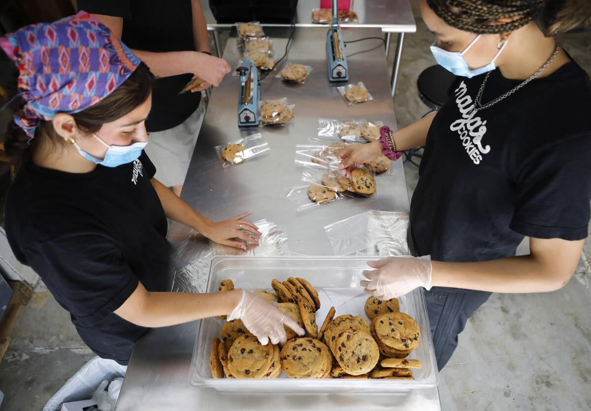 Bella Palacios, left, and Jayden Cunningham package cookies at Maya's Cookies 