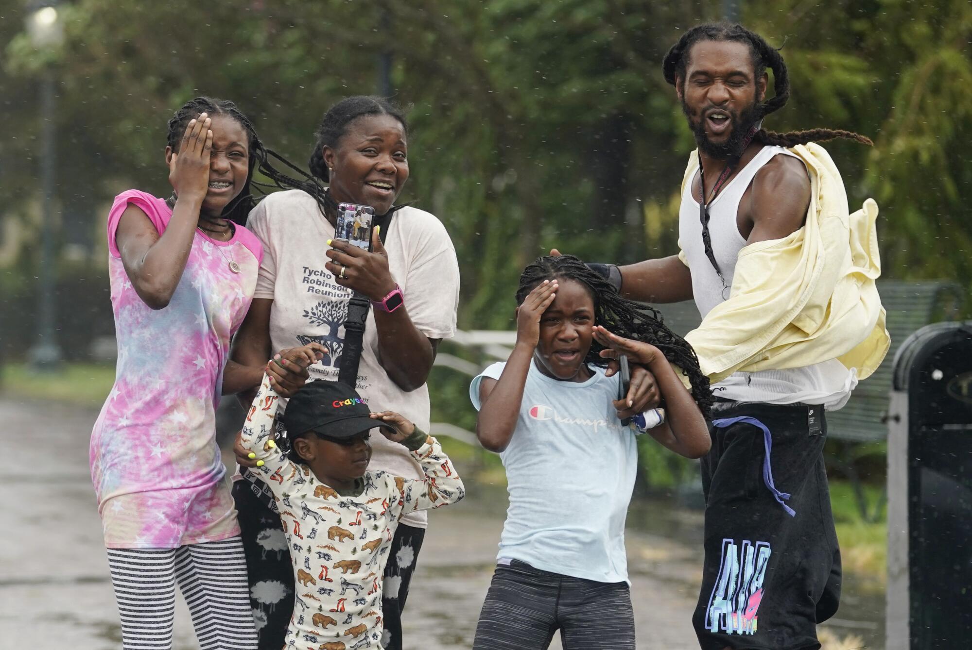 Children and adults stand in rain and wind.