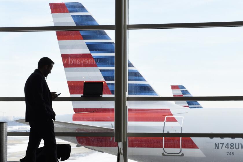 FILE - In this Jan. 25, 2016, file photo, a passenger talks on the phone as American Airlines jets sit parked at their gates at Washington's Ronald Reagan National Airport. American Airlines has agreed to pay $200 million for a stake in China Southern Airlines, the biggest of China's three major state-owned carriers, in a bid for a bigger share of the country's growing travel market. (AP Photo/Susan Walsh, File)