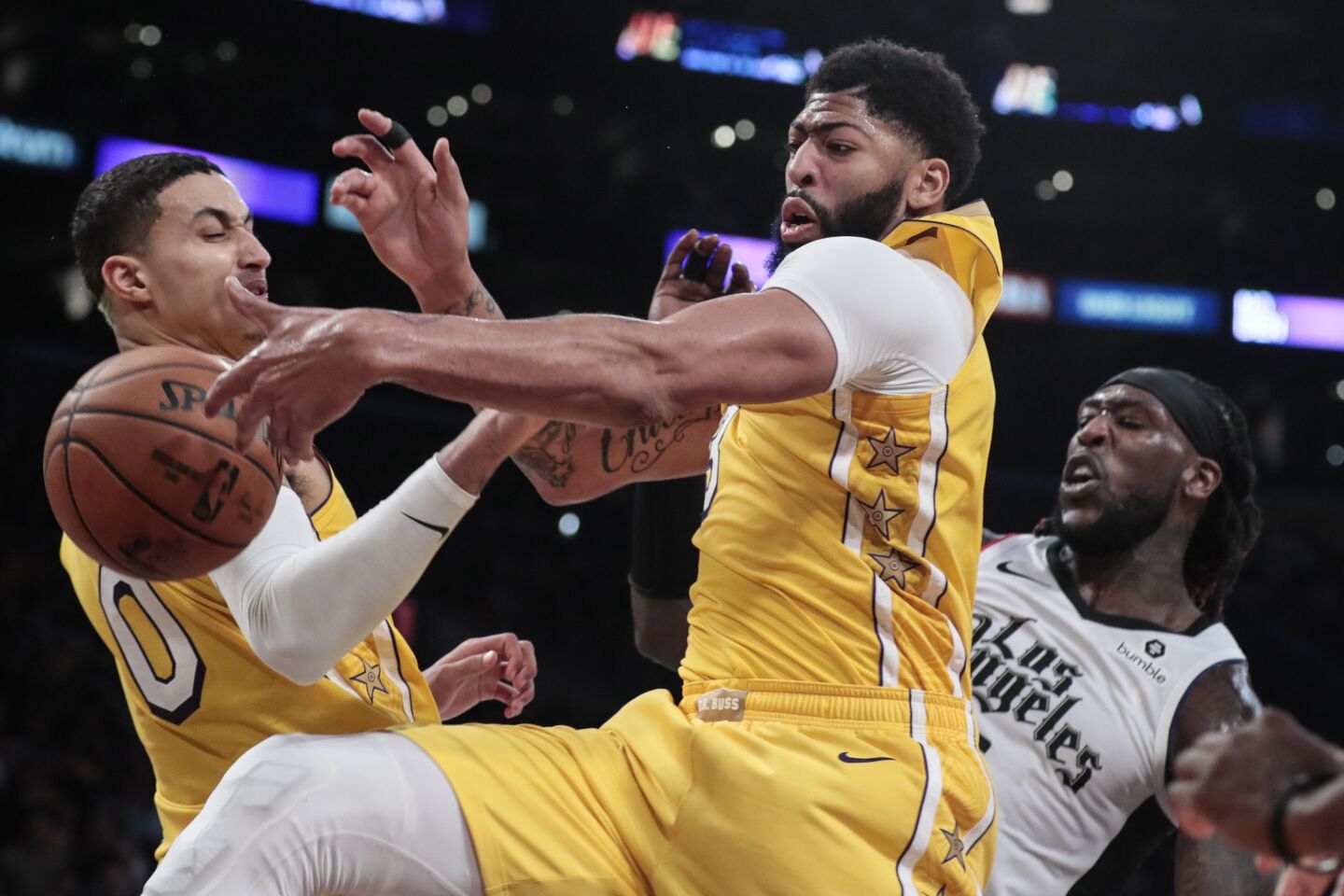 Lakers forwards Kyle Kuzma (0) and Anthony Davis battle Clippers center Montrezl Harrell for a rebound during the second half.