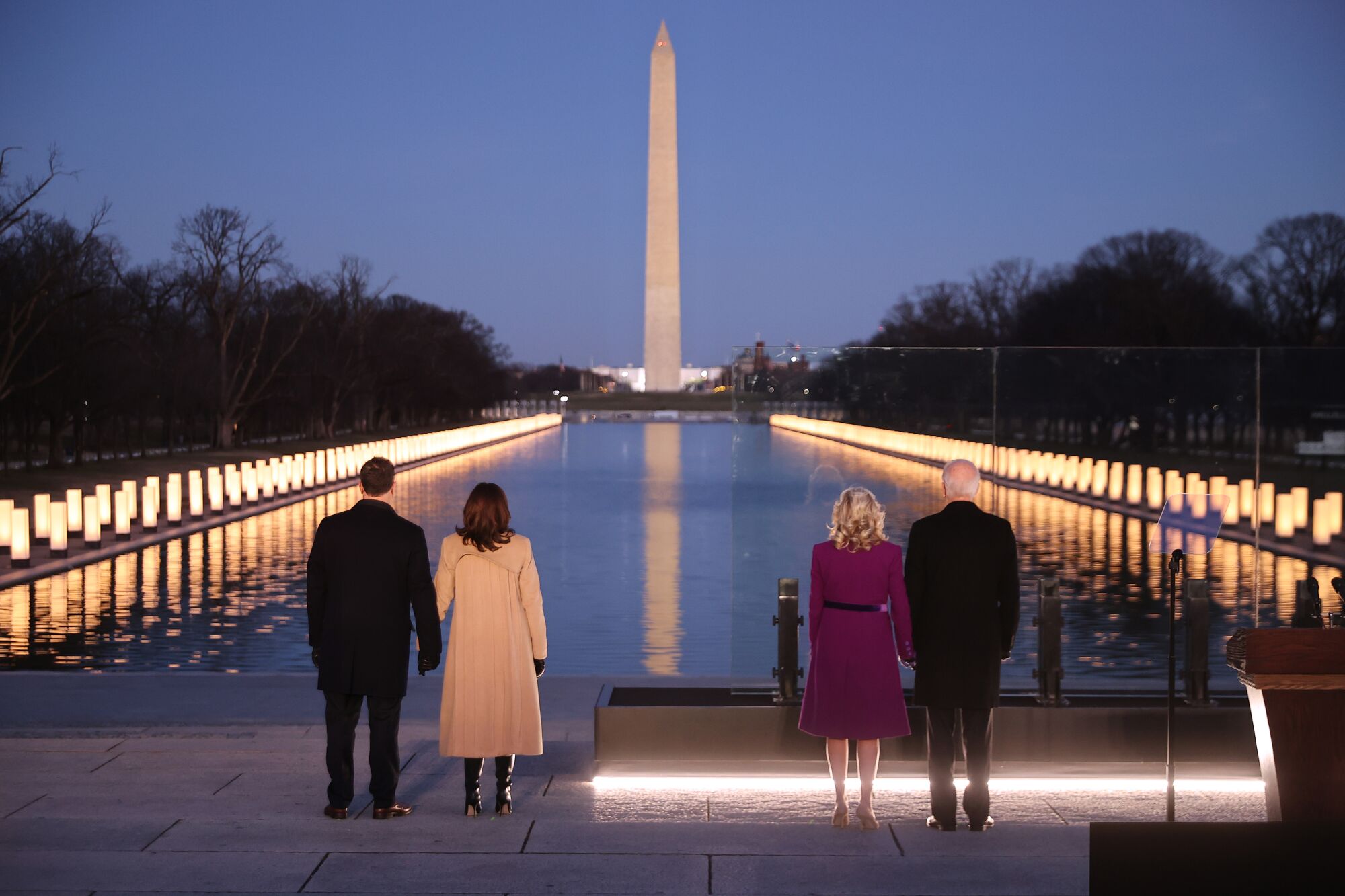 Doug Emhoff, Kamala Harris, Jill Biden and Joe Biden look at lighted lamps at the Lincoln Memorial Reflecting Pool