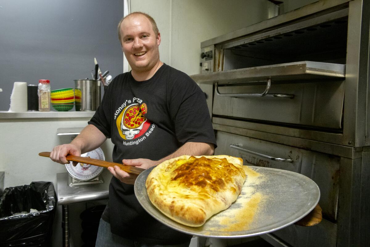 David Skulavik takes Mayor Erik Petersen's 6-pound calzone out of the oven at Stoney's Pizza in Huntington Beach.