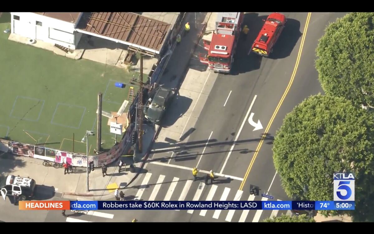 Aerial view of firetrucks and police cars around a green SUV that crashed into a bus stop