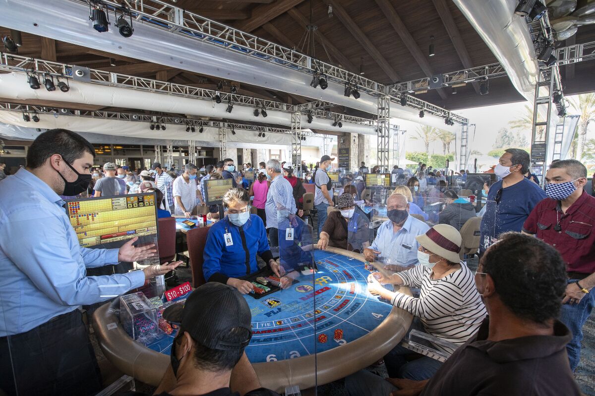 People wearing masks at an outdoor casino setup under a wood covering