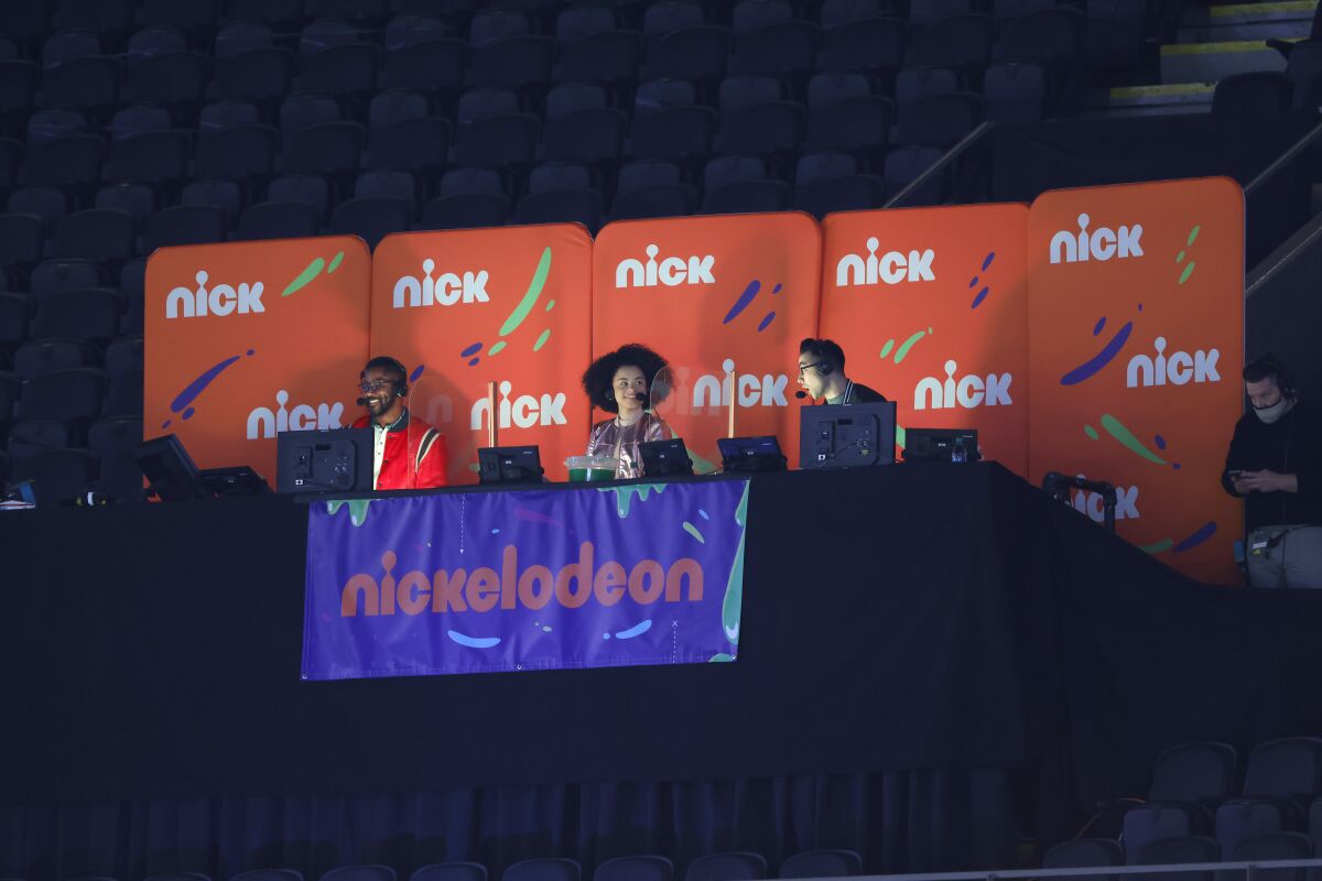 FILE - Nickelodeon commentators Nate Burleson, Gabrielle Nevaeh Green, and Noah Eagle are seen during an NFL wild-card playoff football between the New Orleans Saints and the Chicago Bears, Sunday, Jan. 10, 2021, in New Orleans. Nickelodeon is back again for the opening weekend of the NFL Playoffs this year with more slime and hoping to top last year's critically acclaimed broadcast. The network will do a kids-focused broadcast of the San Francisco 49ers-Dallas Cowboys game on Sunday. (AP Photo/Tyler Kaufman, File)