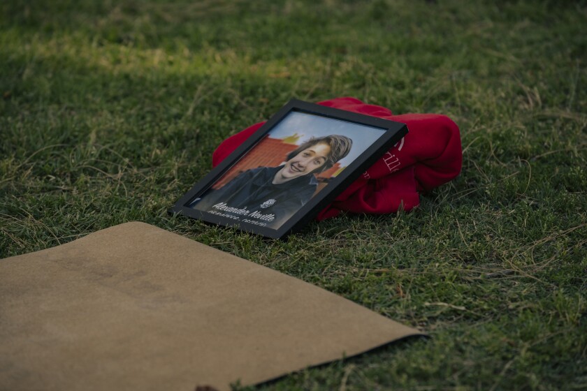 A framed photo of a young man leans on a sweater next to a yoga mat on the grass.