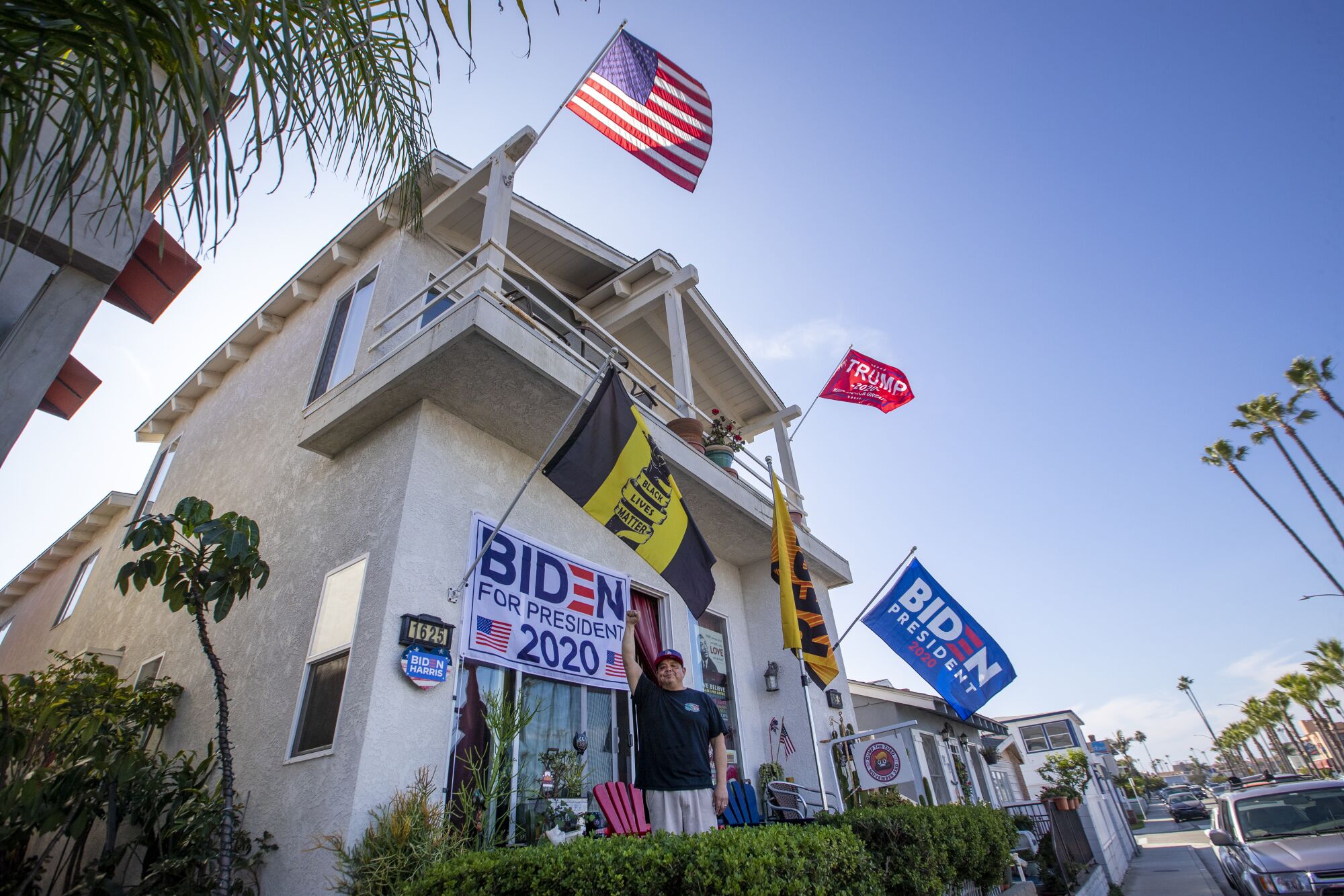 A Joe Biden supporter stands among his supportive flags in front of his home.